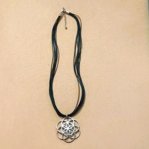 Silver pendant on thin black rubber material band.